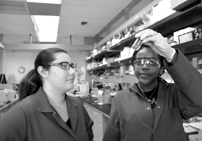 Undergraduate students Catherine Barrie and Akilah Miller look at precursor material they prepared for flexible
batteries.